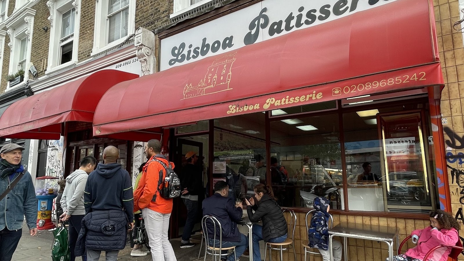 The red awning and busy pavement tables outside Lisboa Patisserie on Golborne Road